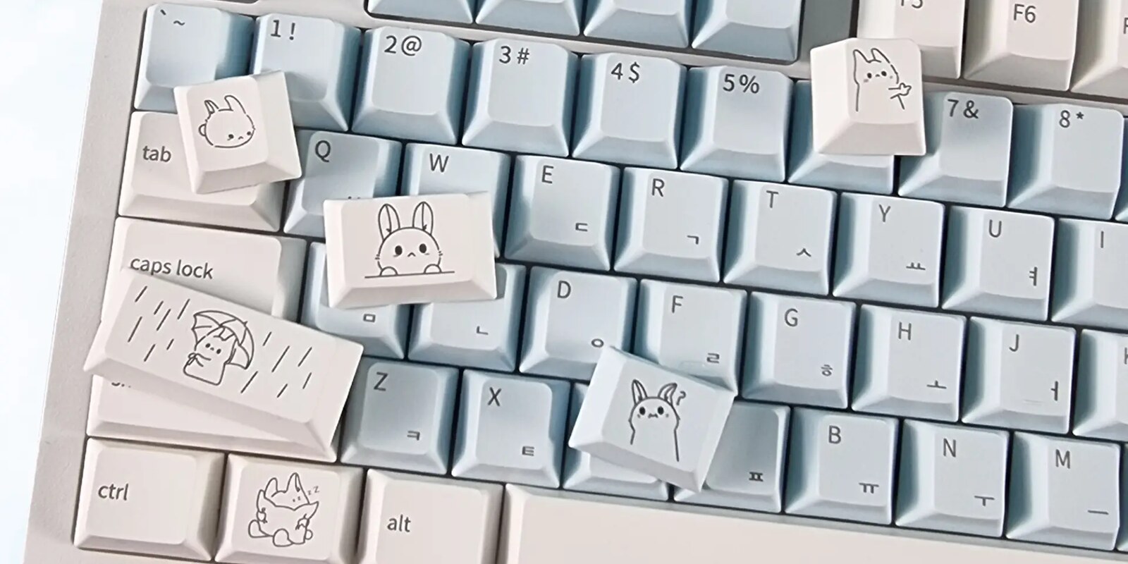 Typeko bunny keycaps scattered on a light blue keyboard